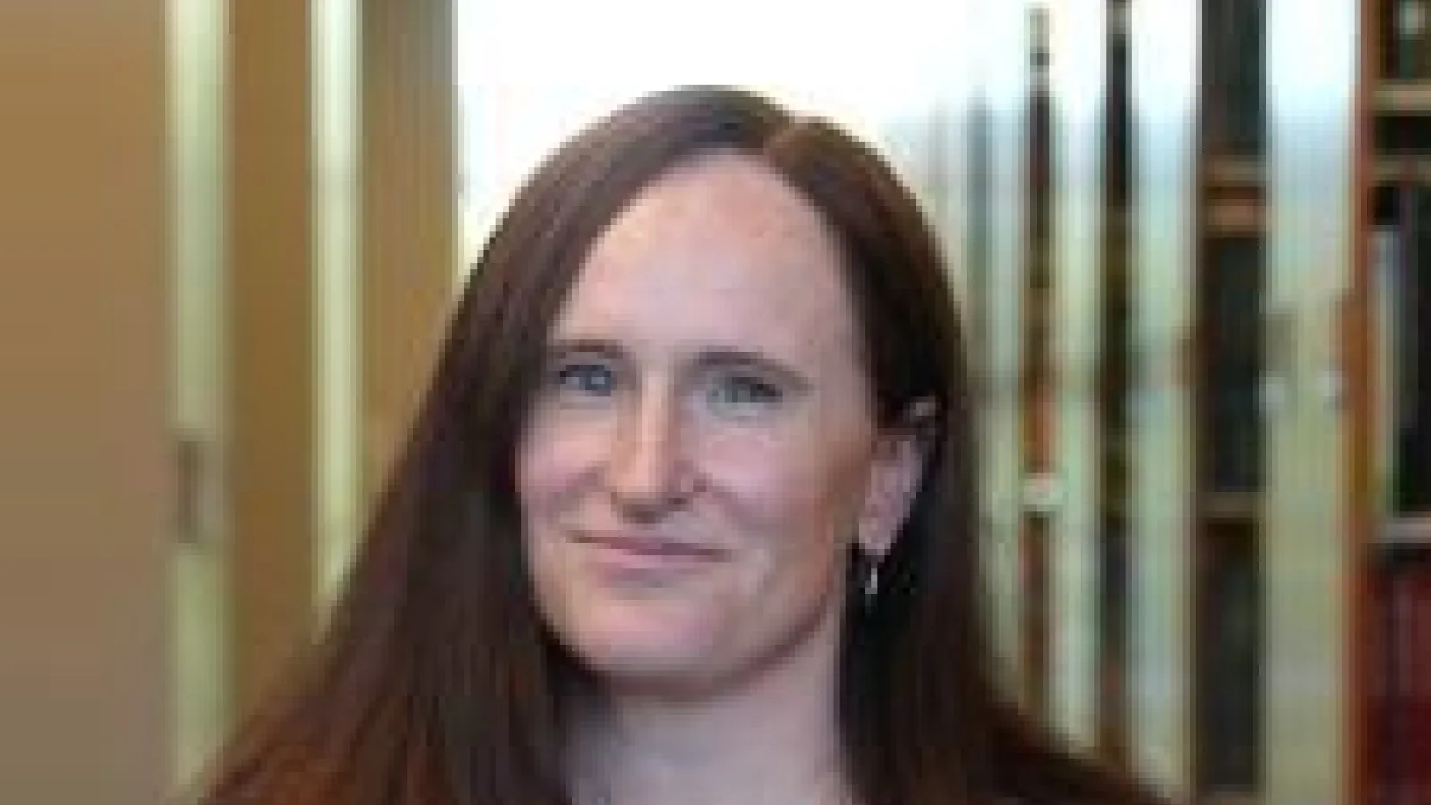 Woman with brown hair in a dark green shirt.