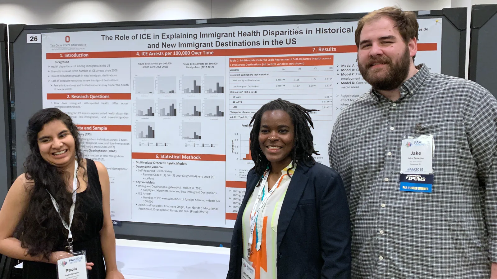 Three graduate students stand by their poster presentation at a PAA conference