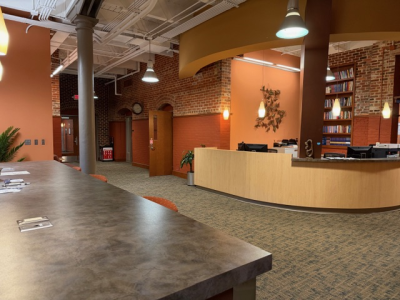 IPR office suite open area painted orange with exposed brick walls and including a reception desk and hanging lights.